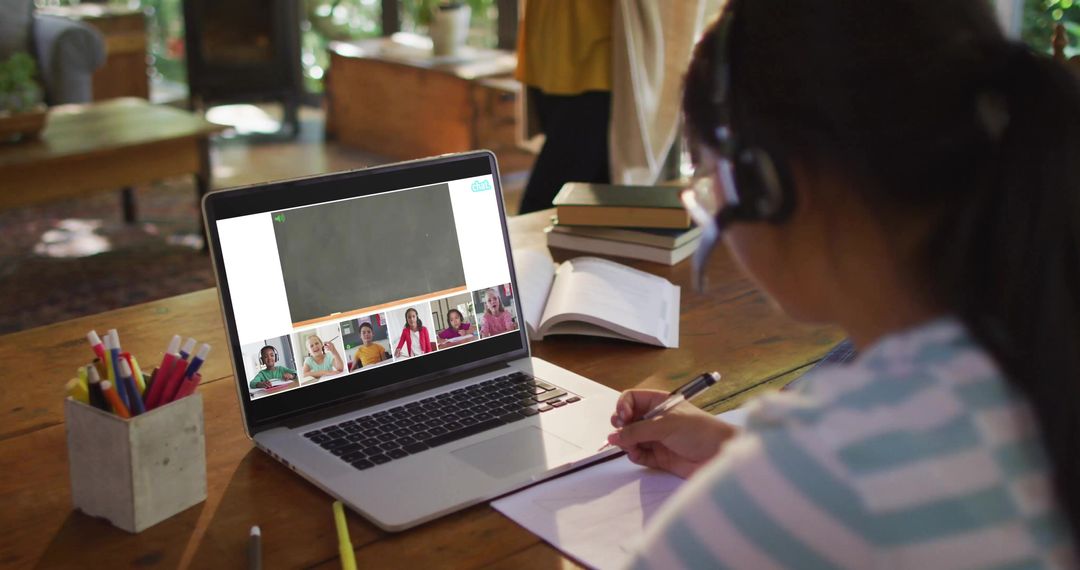 Girl Wearing Headset Studying at Home Taking Notes During Online Class on Laptop