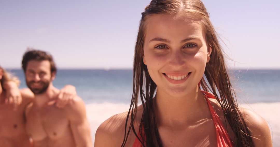 Young Woman Smiling on Beach, Friends in Background - Free Images, Stock Photos and Pictures on Pikwizard.com