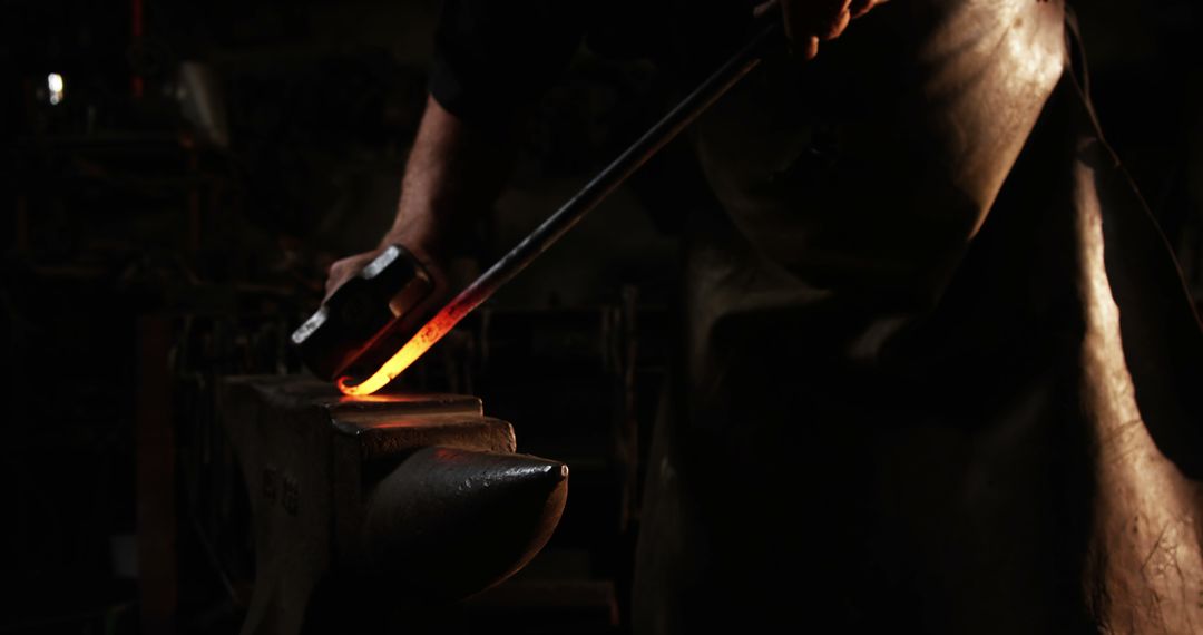 Blacksmith Hammering Glowing Metal in Dim Workshop - Free Images, Stock Photos and Pictures on Pikwizard.com