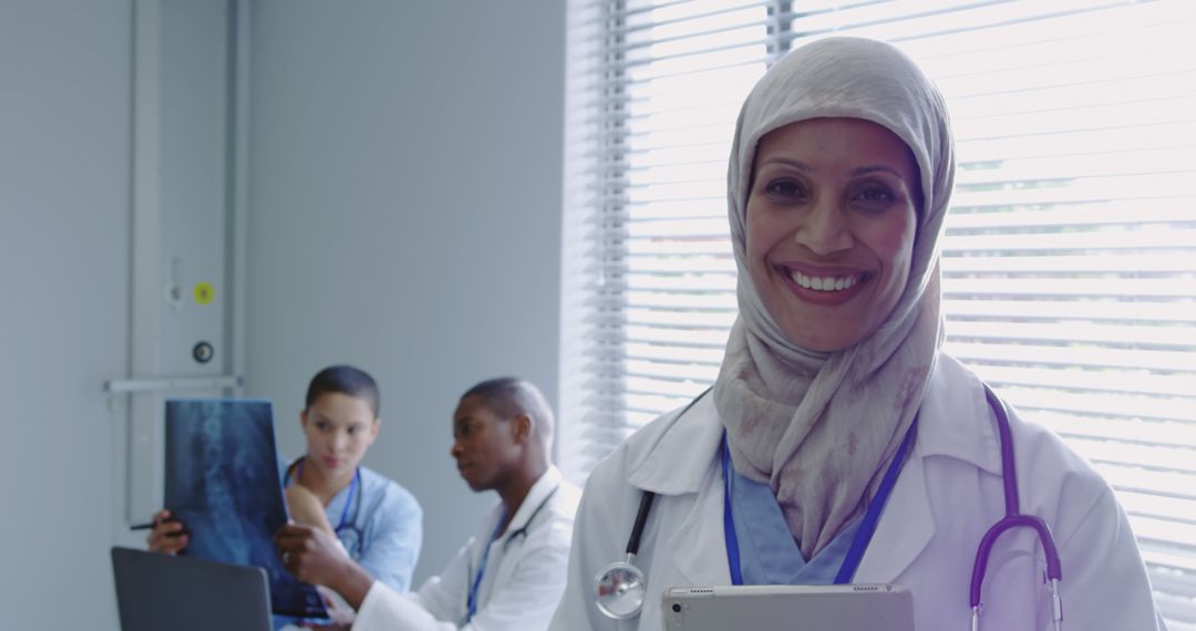 Confident Female Muslim Doctor Smiling in Hospital with Colleagues - Free Images, Stock Photos and Pictures on Pikwizard.com