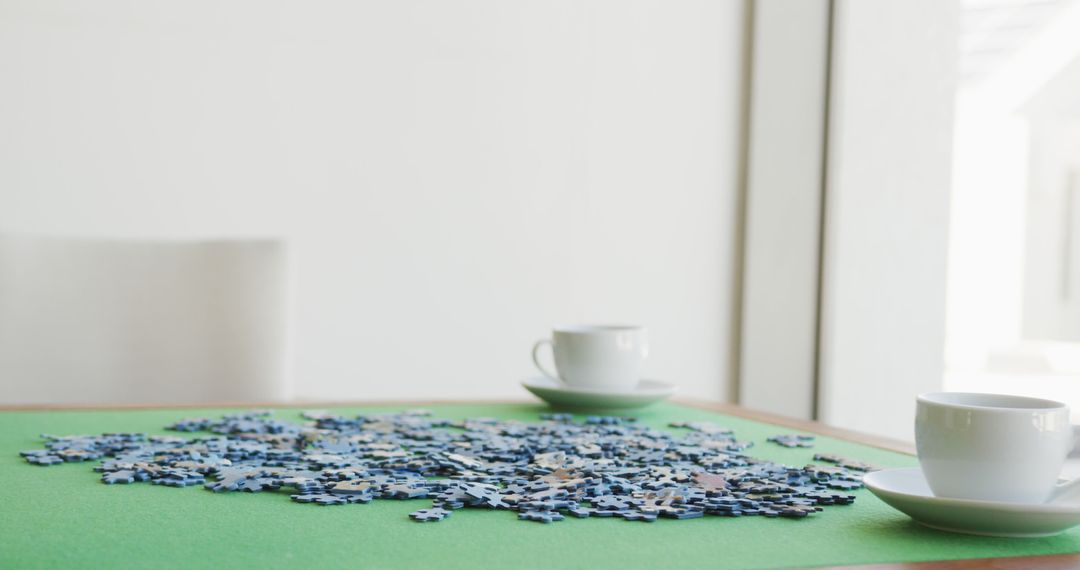 Image of puzzles and cups of coffee on green table - Free Images, Stock Photos and Pictures on Pikwizard.com