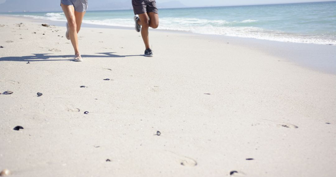 Beachside Joggers Creating Footprints in Sand