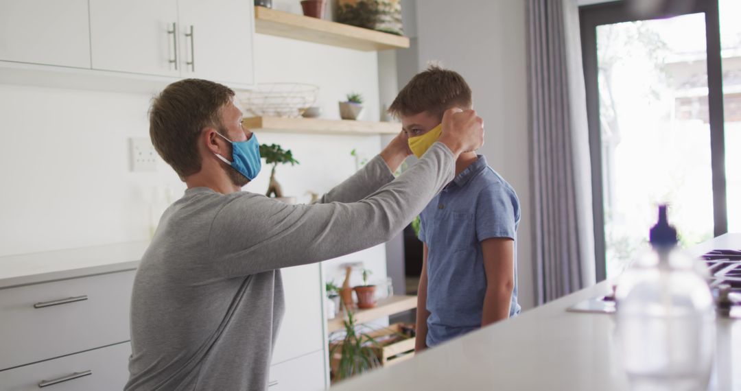 Father Helping Son Wear Protective Face Mask in Modern Kitchen - Free Images, Stock Photos and Pictures on Pikwizard.com