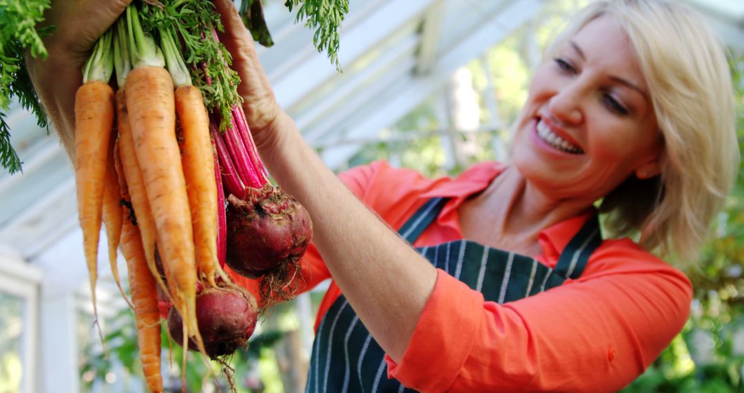 Woman Holding Freshly Harvested Vegetables in a Greenhouse - Free Images, Stock Photos and Pictures on Pikwizard.com