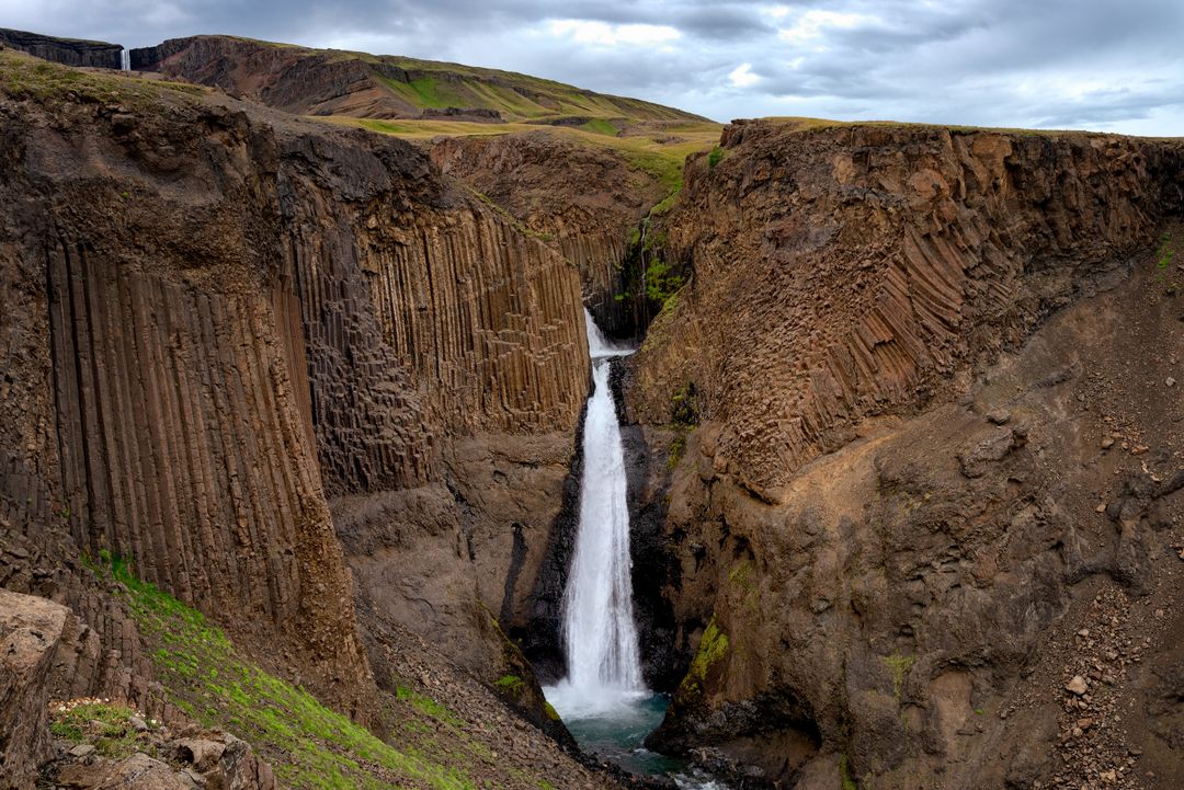 Waterfall Cascading Through Basalt Columns in Rugged Volcanic Canyon, Iceland