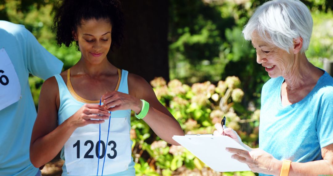 Female Jogger Adjusting Number While Senior Volunteer Making Notes - Free Images, Stock Photos and Pictures on Pikwizard.com