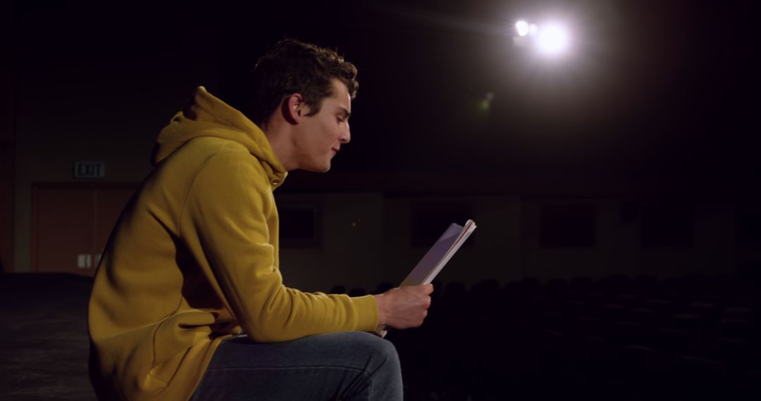 Young Man Rehearsing Lines on Dimly Lit Stage - Free Images, Stock Photos and Pictures on Pikwizard.com