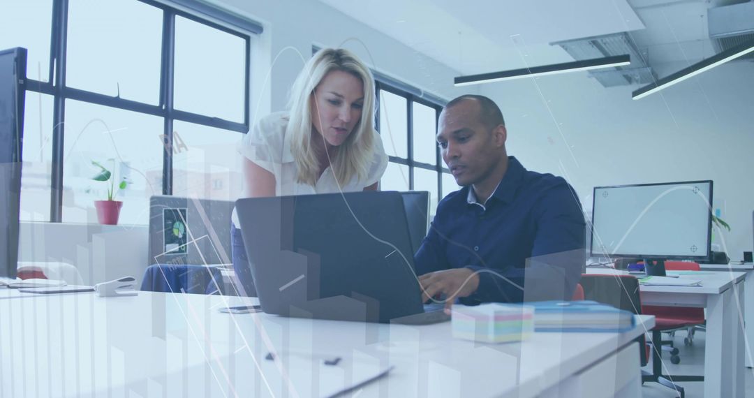 Colleagues Collaborating in Open-Plan Office with Laptop