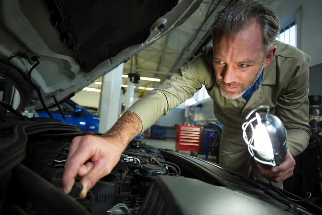 Mechanic examining a car with lamp - Free Images, Stock Photos and Pictures on Pikwizard.com