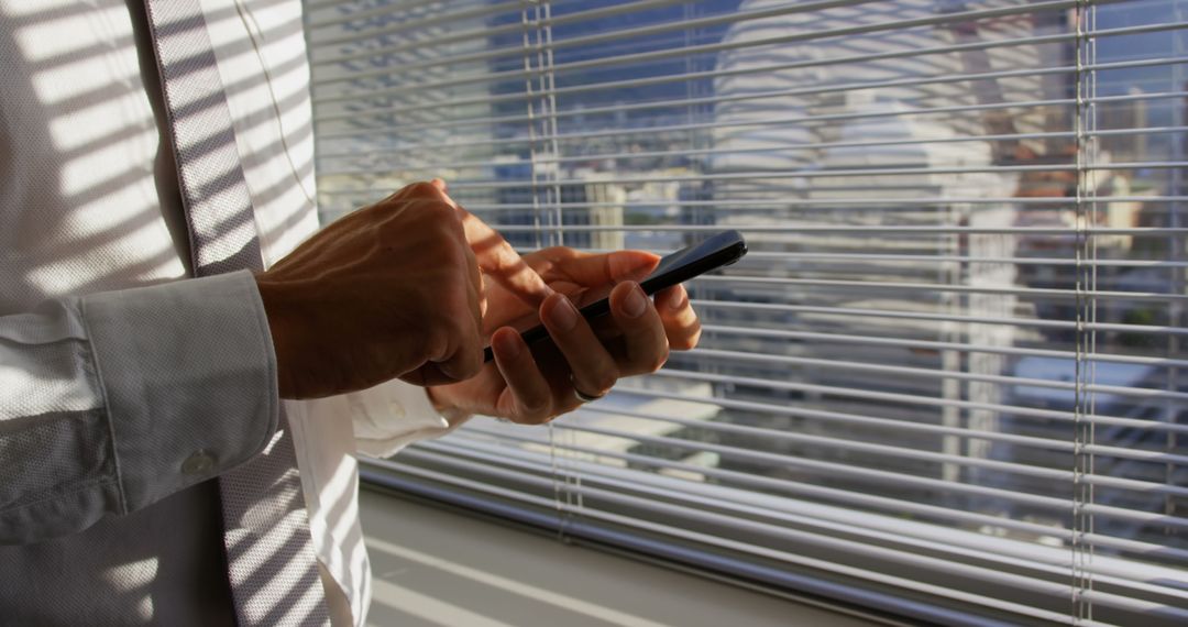 Businessman Texting on Smartphone by Sunny Office Window