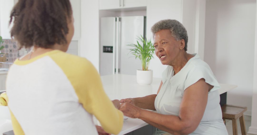 Older Woman Talking to Adult Daughter in Modern Kitchen - Free Images, Stock Photos and Pictures on Pikwizard.com