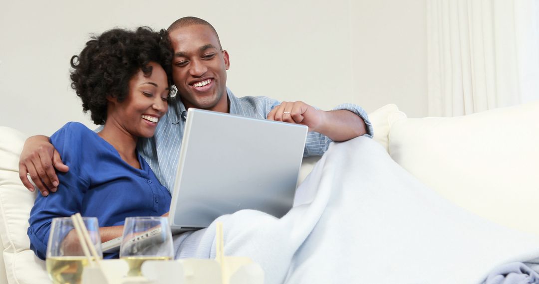 Happy African American Couple Relaxing on Sofa with Laptop