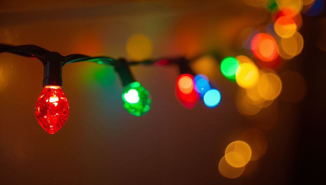 Glowing faceted red bulb on string lights casting colorful bokeh and warm ambient glow