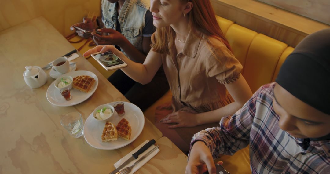 Friends Enjoying Breakfast Waffles in Cafe Using Smartphones - Free Images, Stock Photos and Pictures on Pikwizard.com