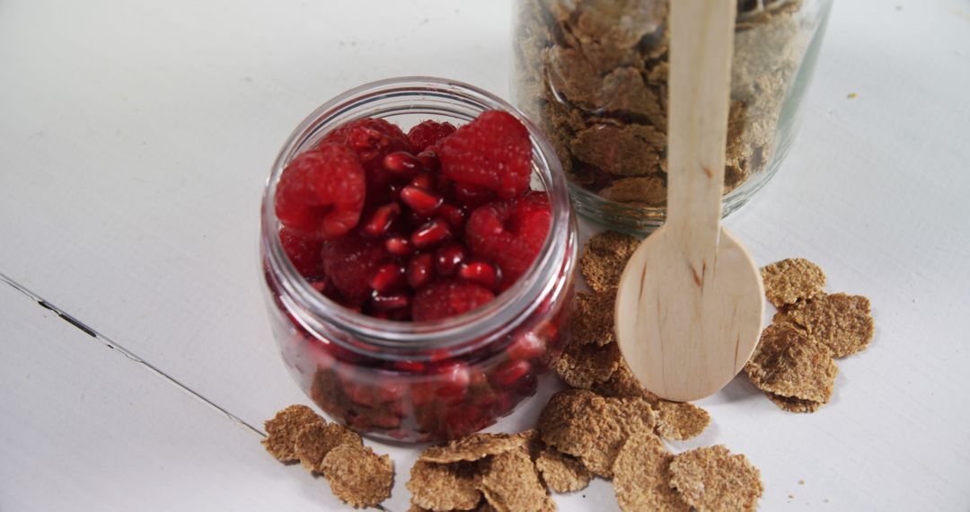 Jar of Fresh Raspberries and Pomegranate Seeds with Bran Flakes - Free Images, Stock Photos and Pictures on Pikwizard.com