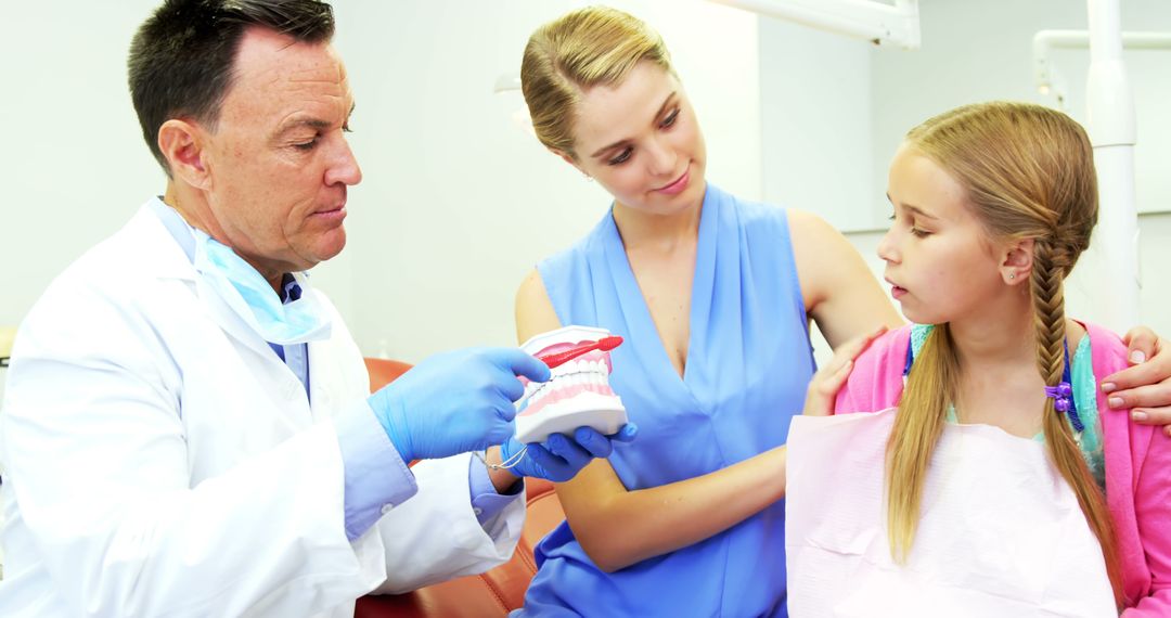 Dentist explaining dental care to mother and daughter in clinic - Free Images, Stock Photos and Pictures on Pikwizard.com