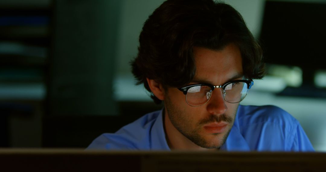 Focused Man Working Late at Computer in Dimly Lit Office - Free Images, Stock Photos and Pictures on Pikwizard.com