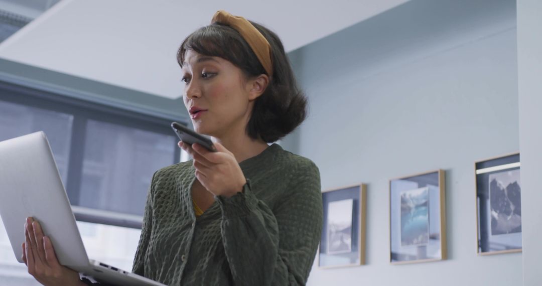 Woman Balancing Laptop and Smartphone in Modern Office Space