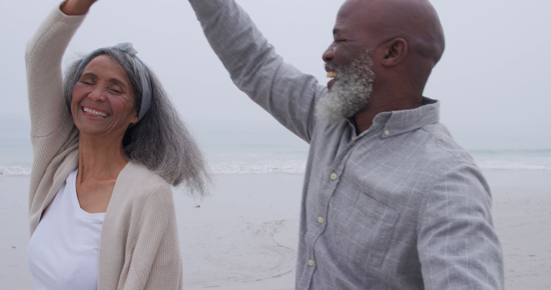 Joyful Couple Dancing on Beach with Ocean Backdrop