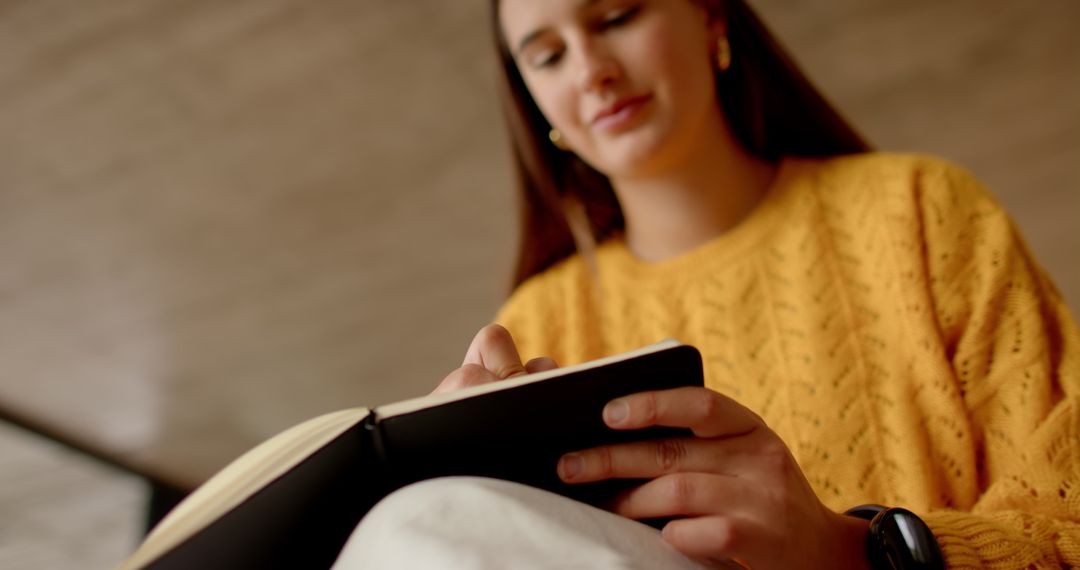 Young Woman Reading Notebook Relaxing with Smartwatch in Cozy Space