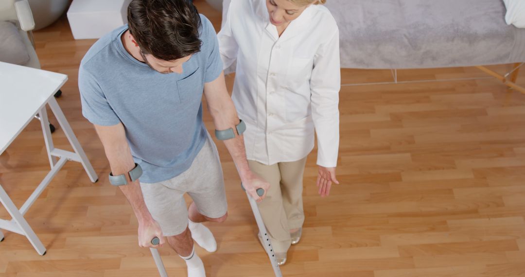 Physical Therapist Assisting Man with Crutches in Rehabilitation Center - Free Images, Stock Photos and Pictures on Pikwizard.com