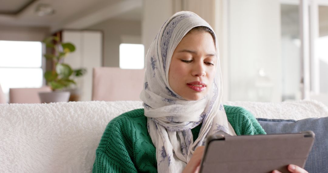 Muslim Woman Using Tablet in Modern Living Room - Free Images, Stock Photos and Pictures on Pikwizard.com