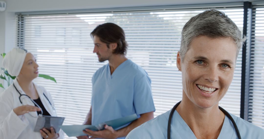 Smiling Doctor with Colleagues Discussing Patient's Health - Free Images, Stock Photos and Pictures on Pikwizard.com