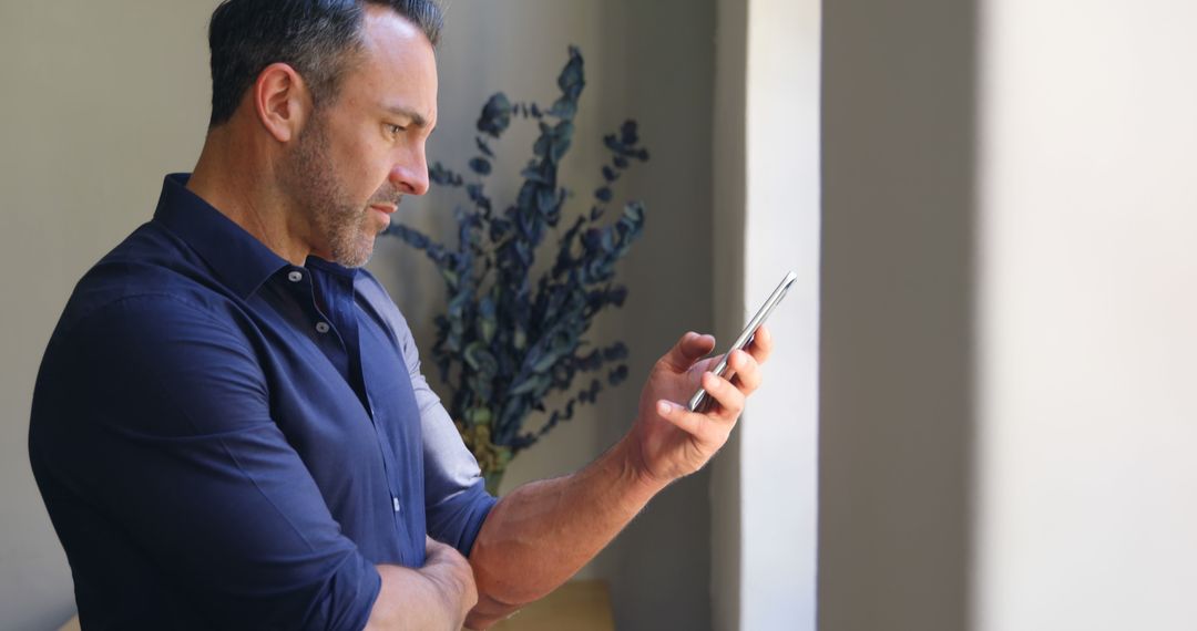 Businessman Checking Smartphone While Standing by Window - Free Images, Stock Photos and Pictures on Pikwizard.com