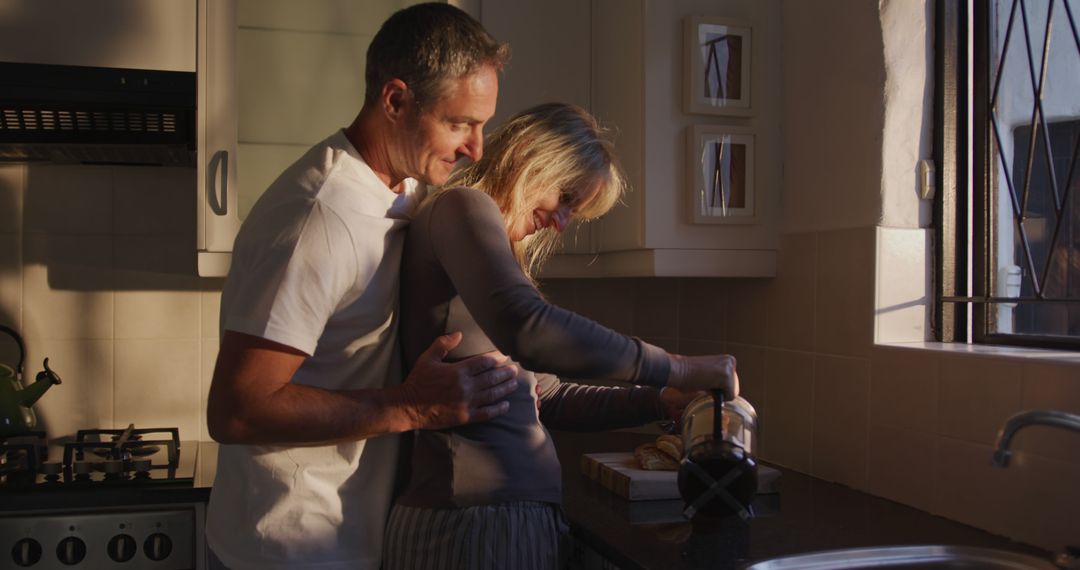 Middle-aged couple sharing intimate moment while preparing breakfast in kitchen - Free Images, Stock Photos and Pictures on Pikwizard.com