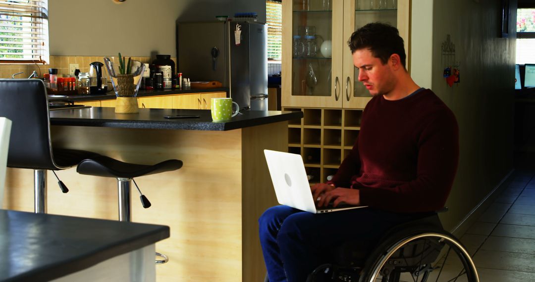 Young Man in Wheelchair Working on Laptop in Cozy Kitchen - Free Images, Stock Photos and Pictures on Pikwizard.com