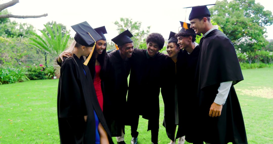 Diverse Graduates Celebrating on Campus Lawn Smiling in Caps Gowns and Colorful Dresses