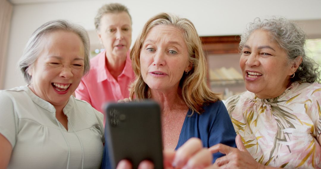 Senior Friends Laughing with Smartphone Indoors