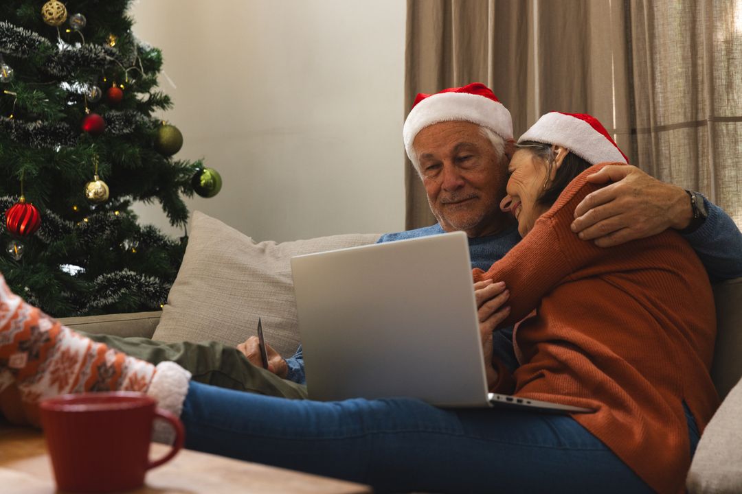 Senior Couple Embracing on Christmas With Laptop and Tree