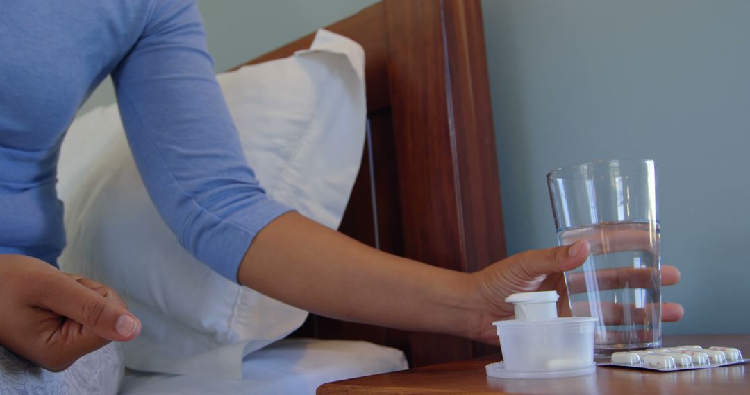 Person Reaching for Water Glass by Bedside with Medications and Alarm Clock - Free Images, Stock Photos and Pictures on Pikwizard.com