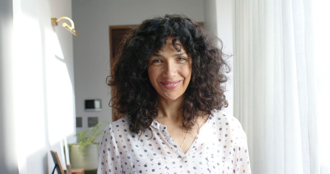 Smiling Woman with Curly Hair in Brightly Lit Room - Free Images, Stock Photos and Pictures on Pikwizard.com