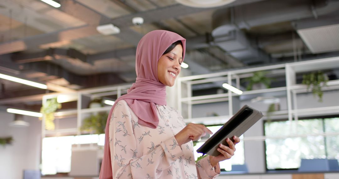 Smiling Businesswoman in Hijab Using Tablet in Modern Office - Free Images, Stock Photos and Pictures on Pikwizard.com