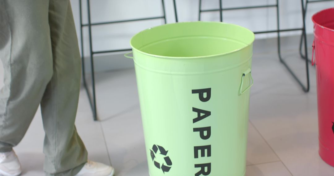 Man Standing by Green Paper Recycling Bin in Modern Office Lobby Breakroom