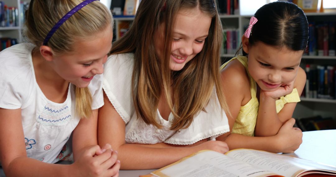 Joyful Schoolgirls Reading Together in Library Setting - Free Images, Stock Photos and Pictures on Pikwizard.com