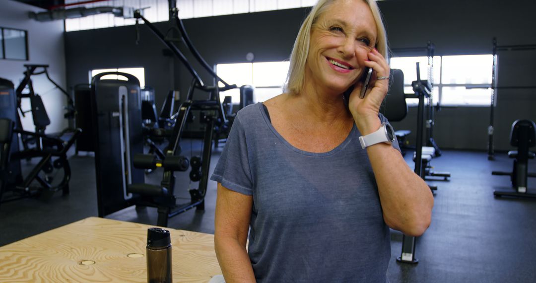 Senior woman talking on smartphone in gym, wearing casual workout attire - Free Images, Stock Photos and Pictures on Pikwizard.com