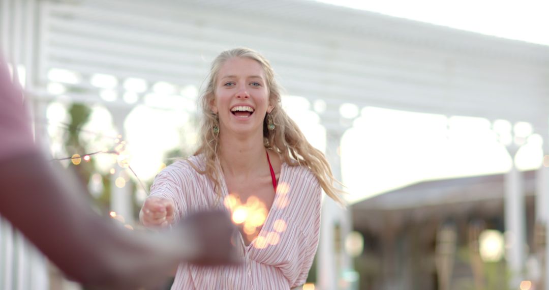 Carefree Woman Smiling and Holding Sparklers Outdoors - Free Images, Stock Photos and Pictures on Pikwizard.com