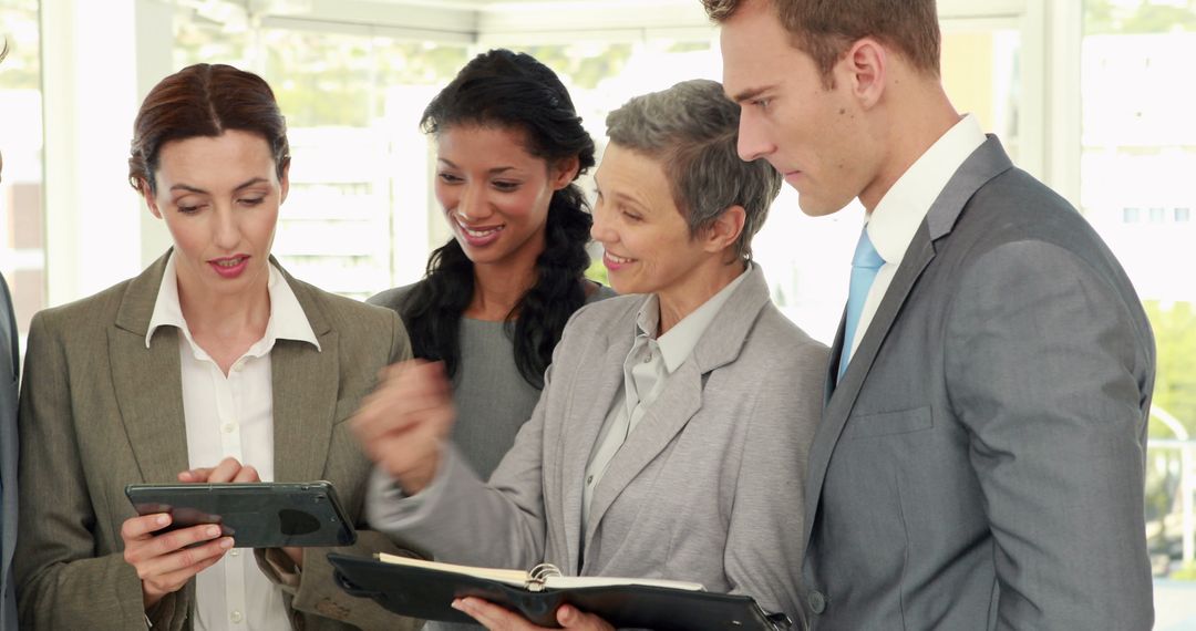 Diverse Business Team Conferring Over Digital Tablet and Documents