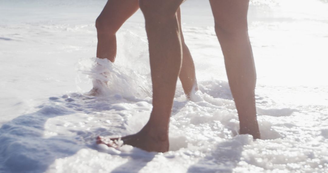 Close-Up of Two People Walking in Ocean Waves on Sunny Day - Free Images, Stock Photos and Pictures on Pikwizard.com