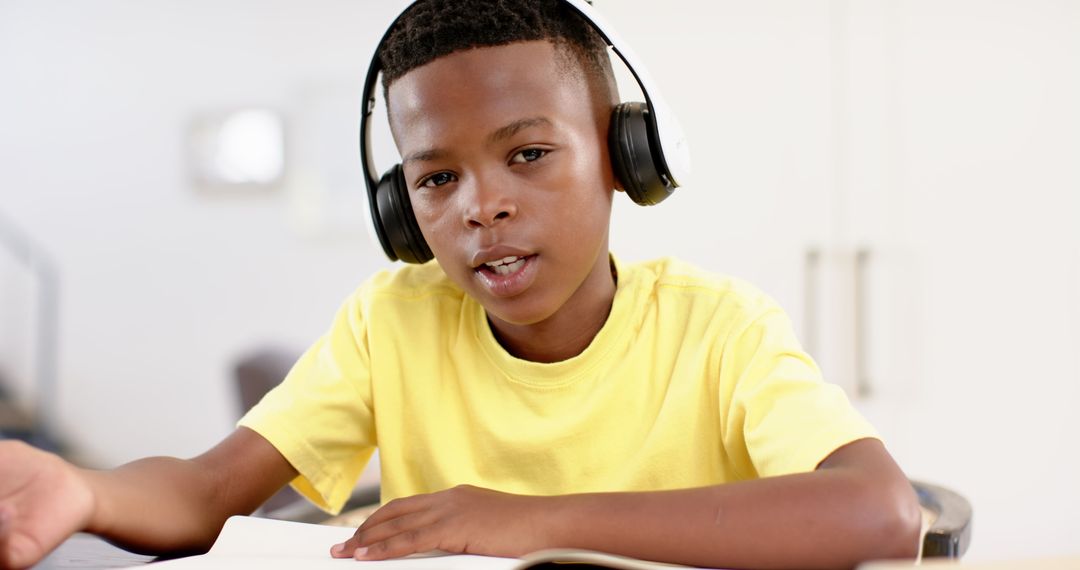 Child with Headphones Studying and Writing in Notebook