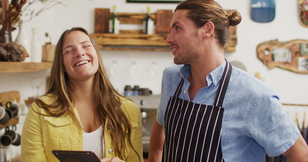 Smiling Cafe Owners Discuss Business with Digital Tablet