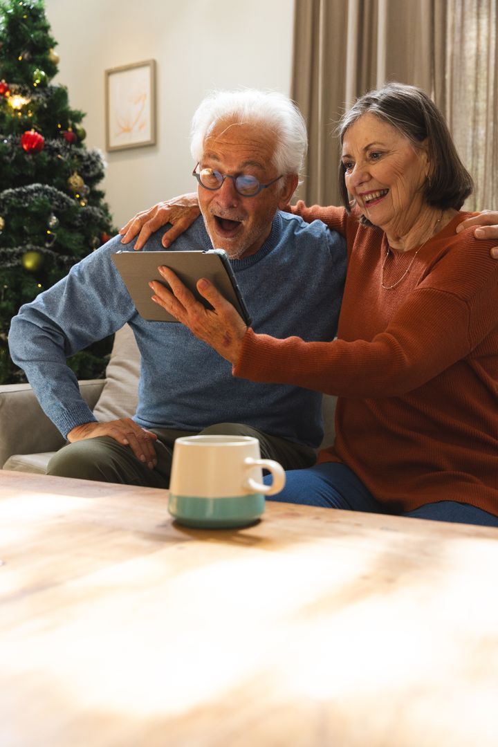 Elderly Couple Joyfully Video Chatting on Tablet during Christmas
