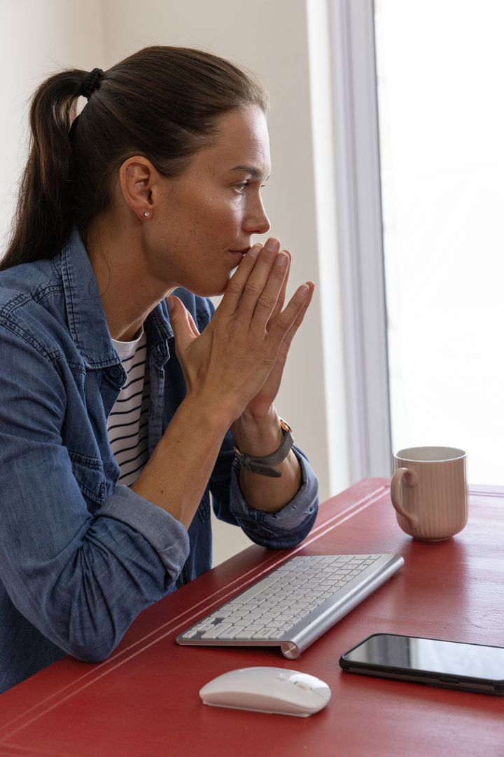 Woman Contemplating at Desk with Keyboard and Smartphone