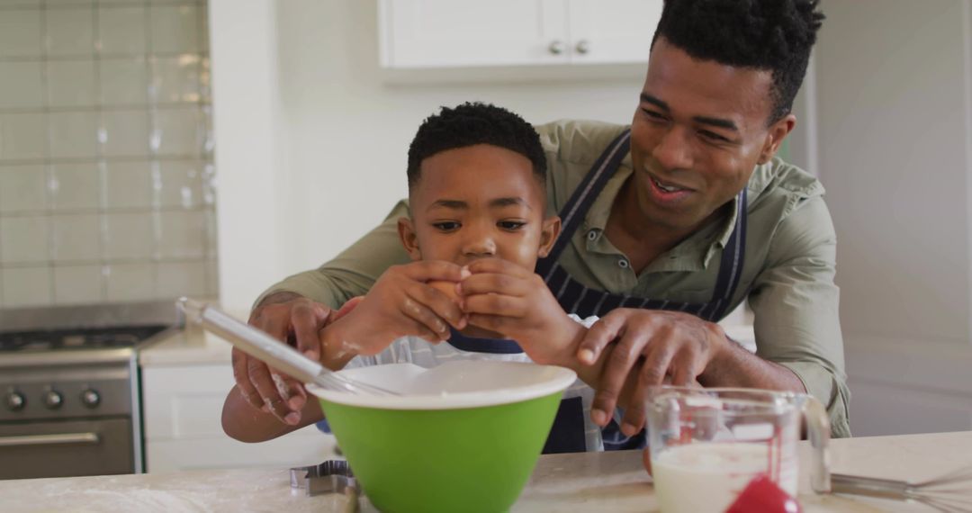 Father Teaching Son Cracking Egg While Baking Together in Bright Home Kitchen