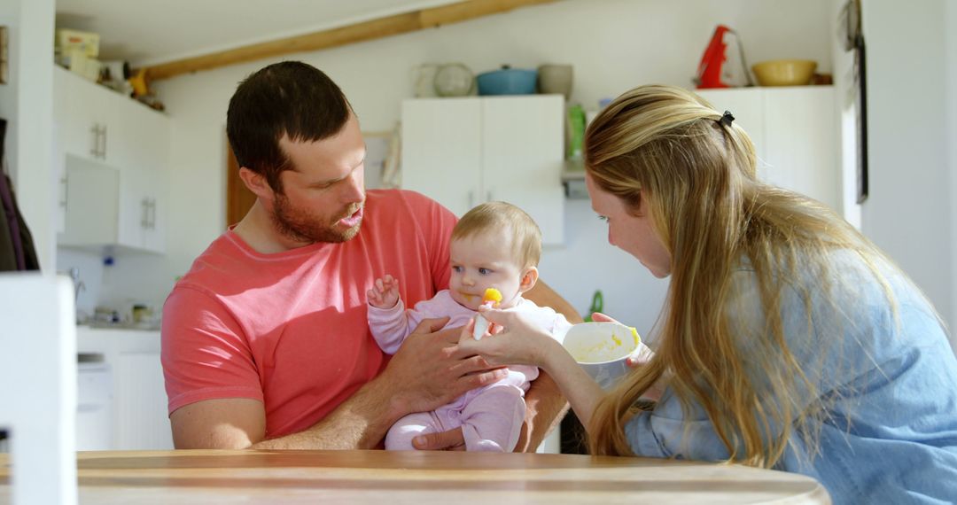 Parents Feeding Baby in Modern Kitchen - Free Images, Stock Photos and Pictures on Pikwizard.com