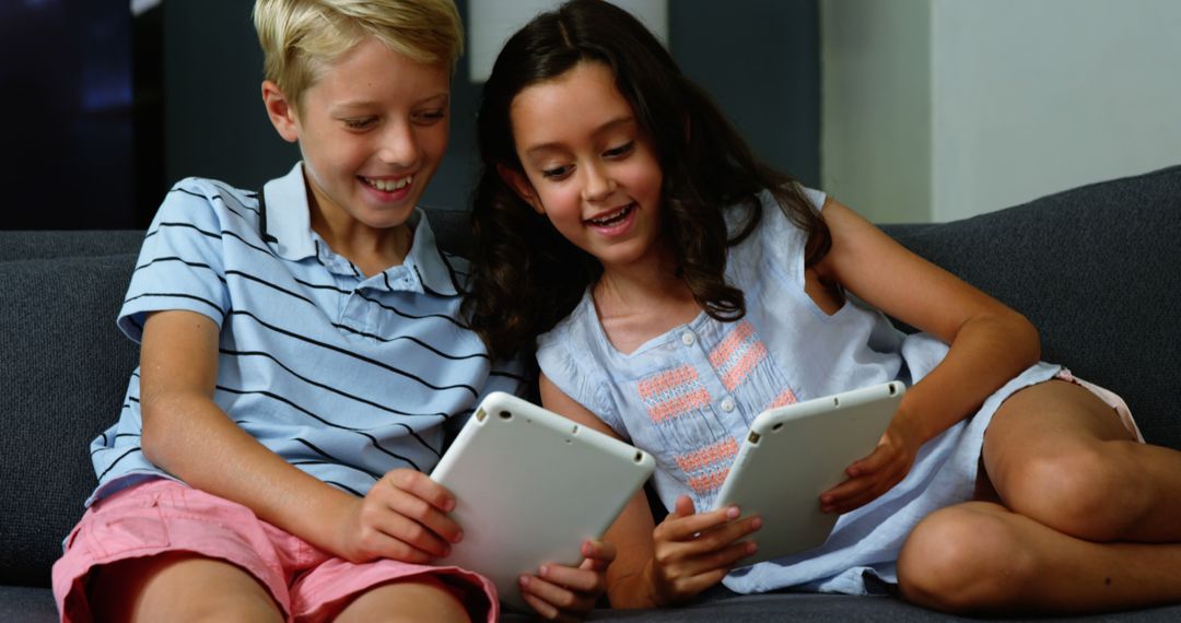 Smiling Kids Sitting on Sofa Using Digital Tablets - Free Images, Stock Photos and Pictures on Pikwizard.com