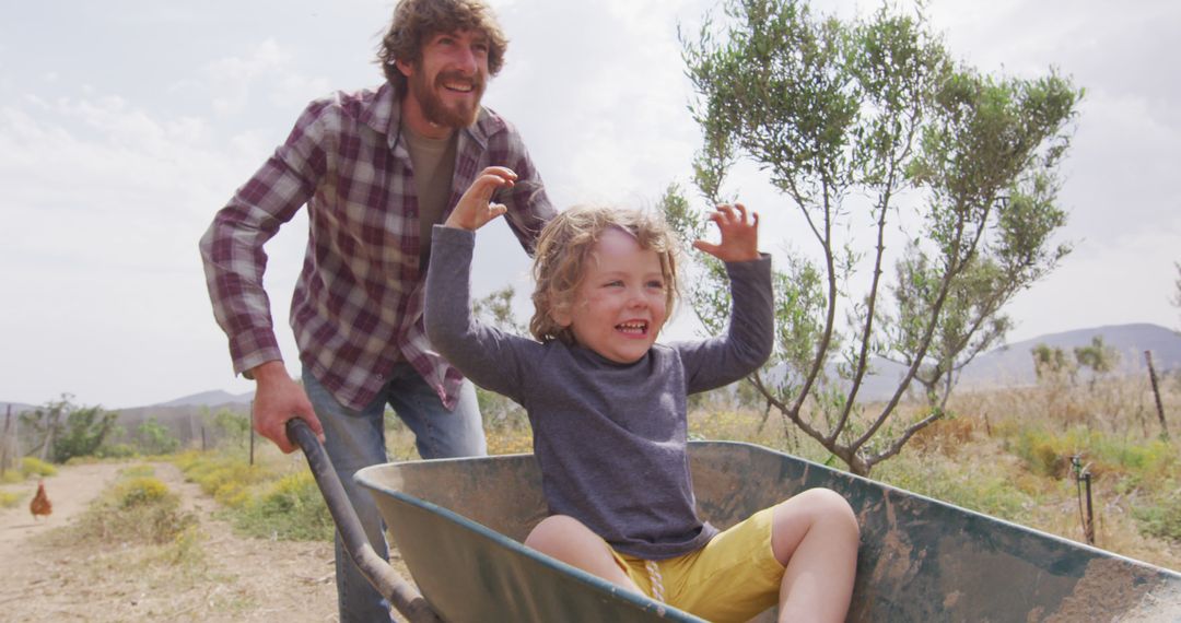 Father Pushing Happy Child in Wheelbarrow Outdoors - Free Images, Stock Photos and Pictures on Pikwizard.com